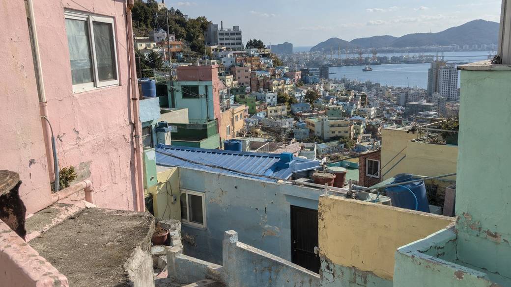 Pastel hillside houses of Gamcheon Culture Village stepping down to Busan's harbour on a clear afternoon