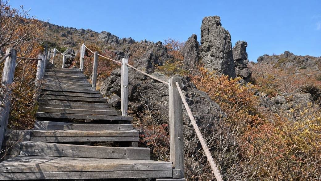 Wooden boardwalk on Hallasan's Yeongsil trail climbing past rock pillars and autumn shrubs