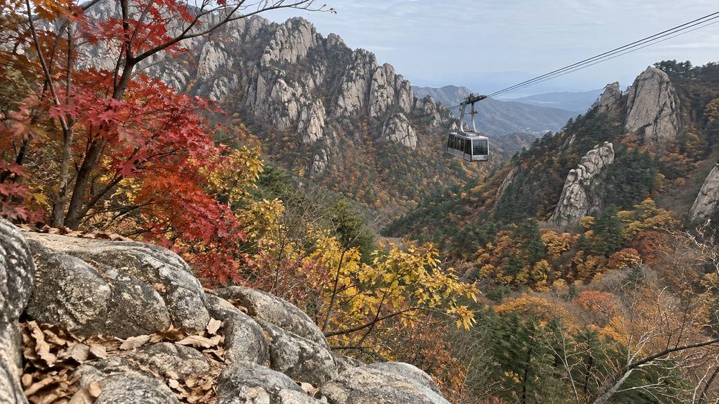 Red maples and yellow oaks on the granite ridges of Seoraksan National Park in late October, a cable car cabin crossing the